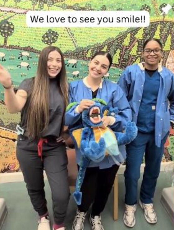 The team holding the tooth mascot in front of a painted farm mural