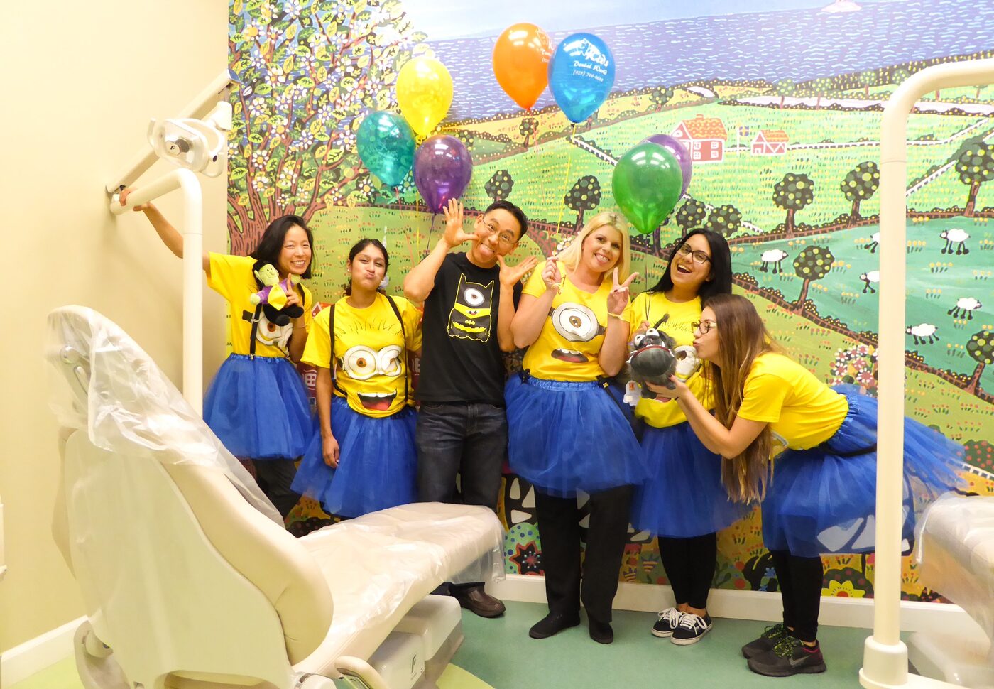 The Kids Dental World team in matching costumes with balloons in the treatment room